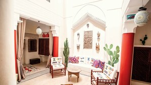 A cozy interior with a white sofa, wooden chairs, a small round table, and a cactus plant.
