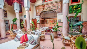 A cozy courtyard with a bed, dining area, and potted plants.