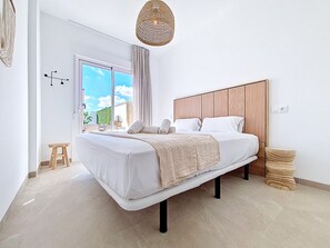 A modern bedroom with a large bed, a wooden headboard, and a view of the outdoors. - Villa with private pool and roof terrace (San Javier)