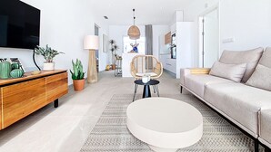 Uma sala de estar moderna com televisão de tela plana, móveis de madeira, uma mesa de centro redonda e um sofá.