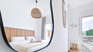 Quarto moderno com um espelho grande, uma cabeceira de madeira e vista para o exterior.