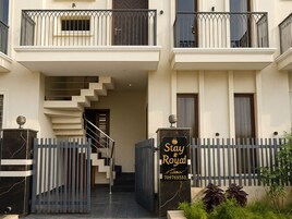 Un edificio de varios pisos con una escalera que lleva a la entrada, un camino de acceso con portón y un letrero que dice 'Stay & Royal'.