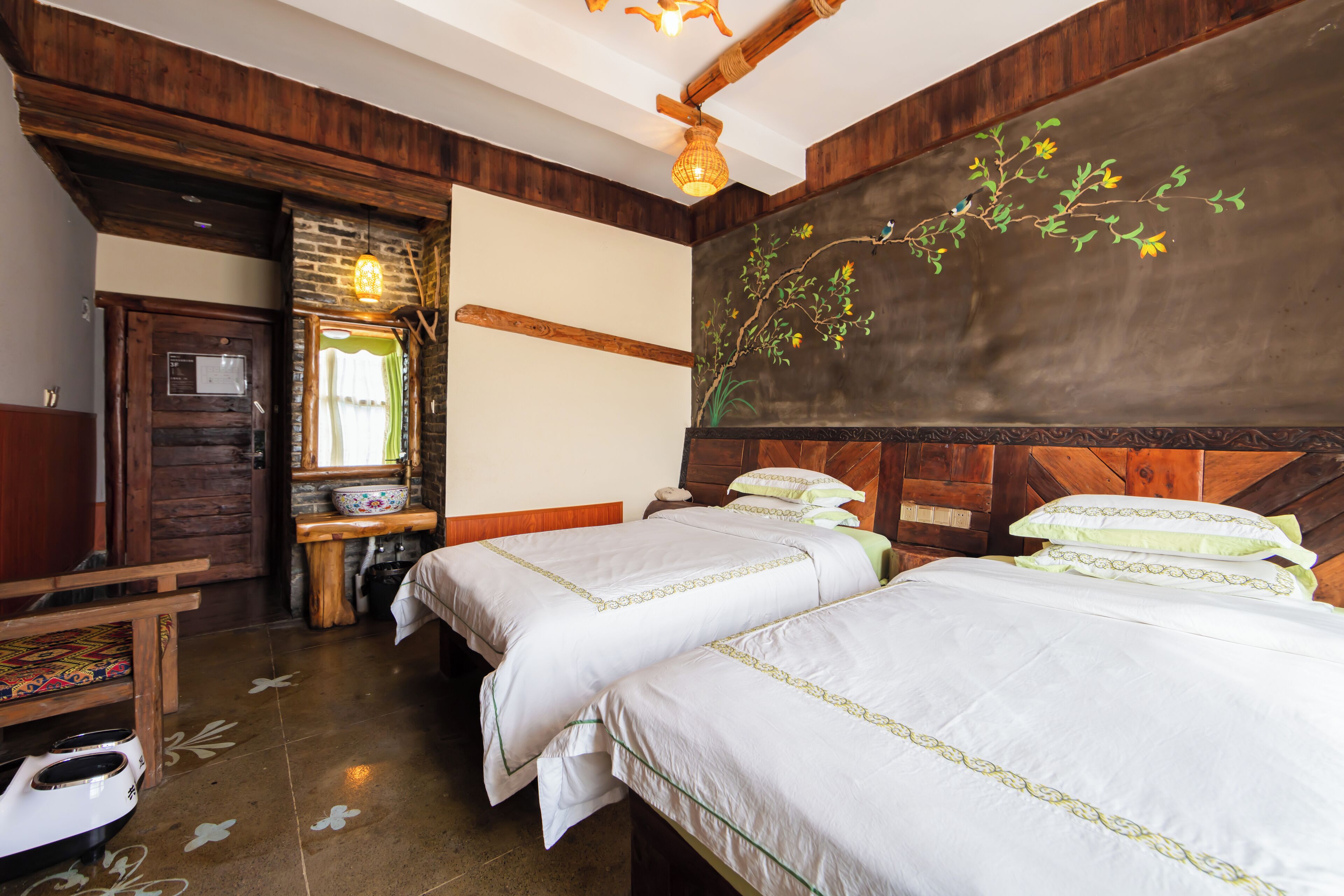 A room with two beds, wooden walls, a stone fireplace, and a rustic wooden ceiling.