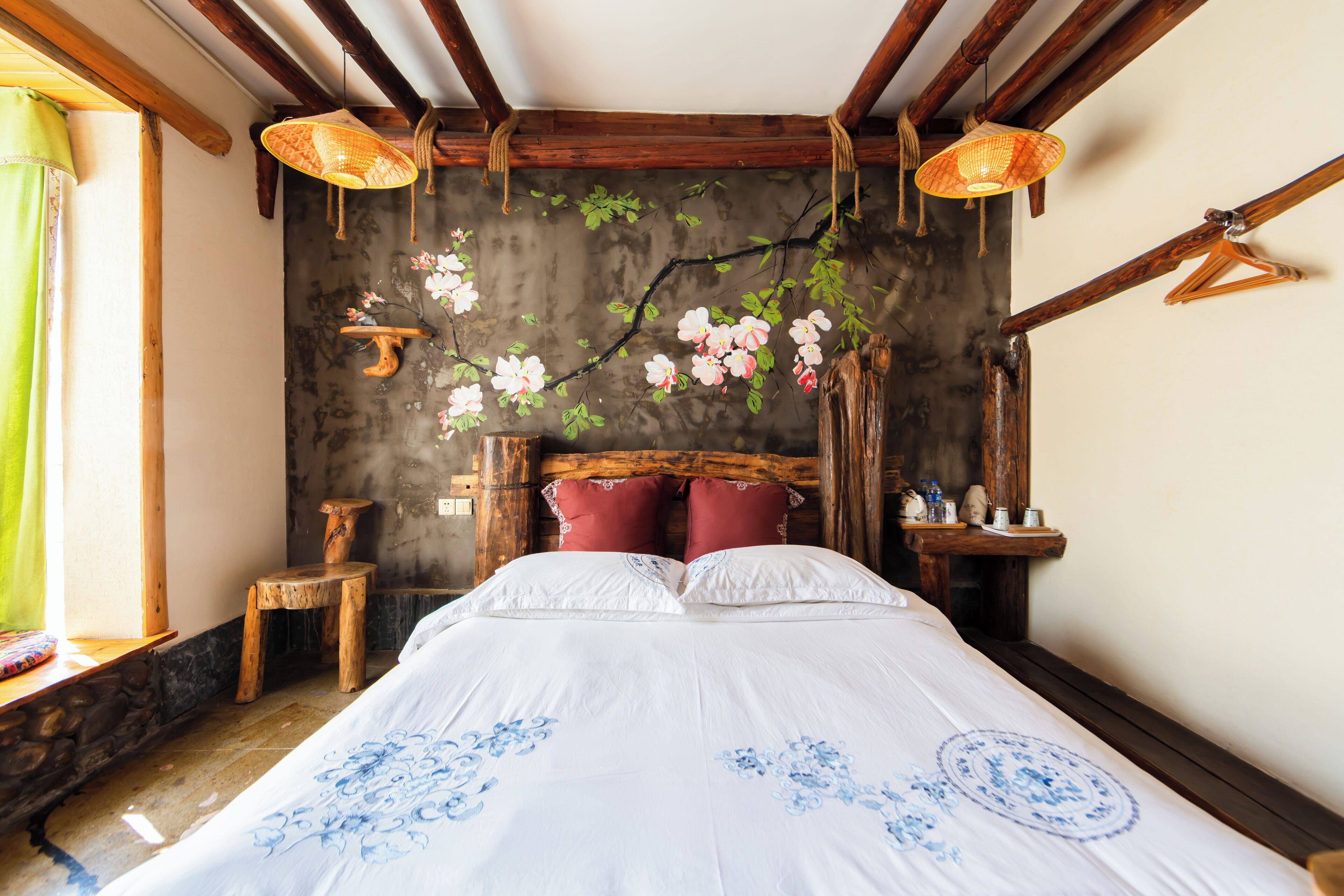 A bedroom with a bed, wooden headboard, hanging lamps, and a wall-mounted shelf.