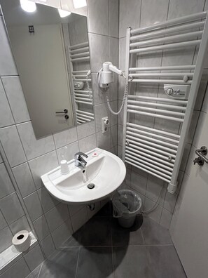 Habitació triple Comfort, vistes al pati | Bany | Capçal de dutxa tipus cascada, sabó, xampú i paper higiènic 