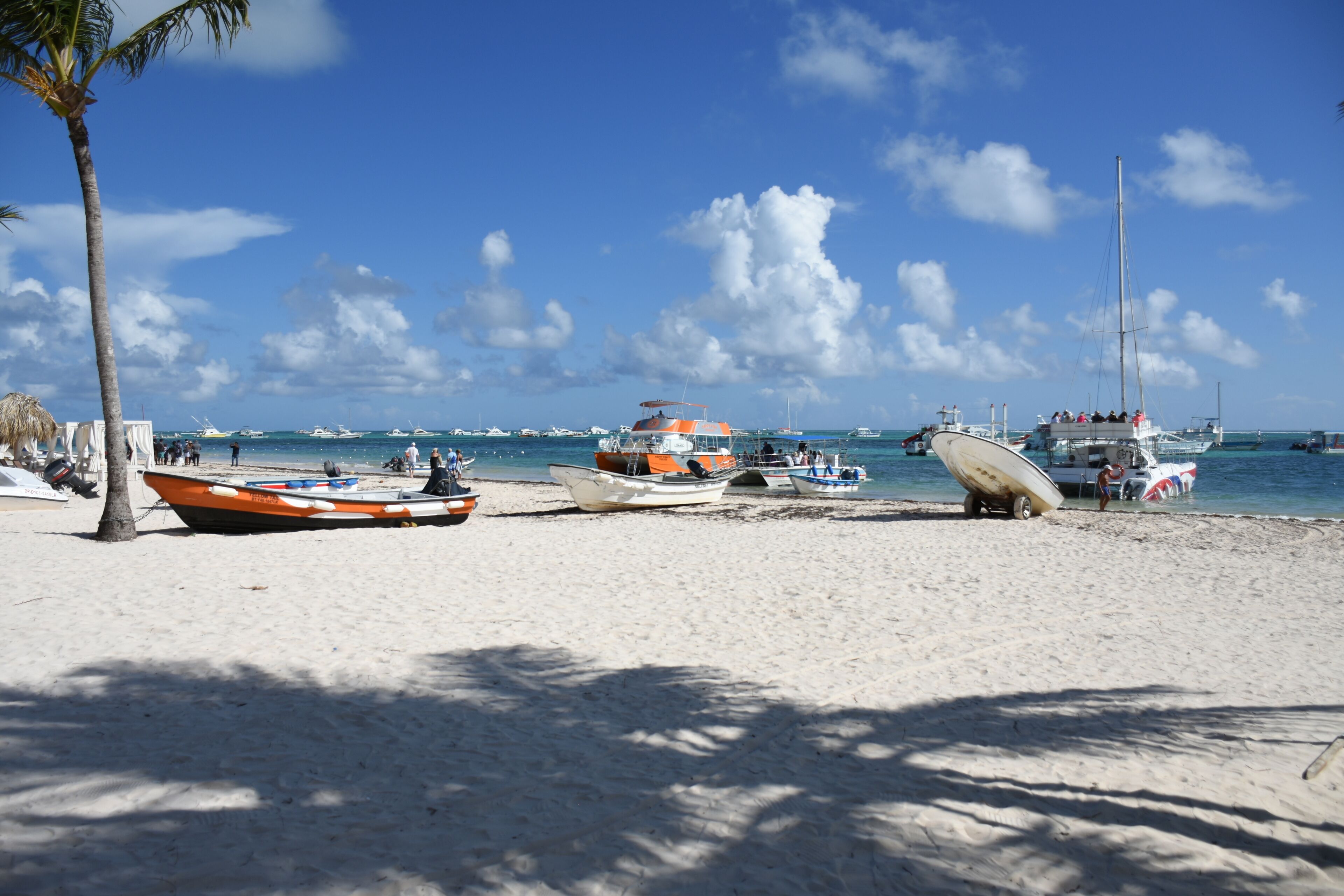 Una playa con varios barcos amarrados y un cielo azul despejado.