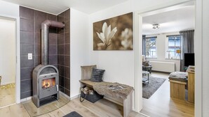 Een moderne woonkamer met een houtkachel, een bank met een bont plaid en een schilderij aan de muur.