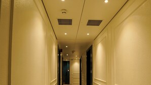 A hotel hallway with patterned carpet, cream walls, and recessed lighting. - The Food Villa (Mumbai)