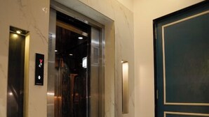 An elevator with a marble floor and a modern design, leading to a room with a dark door. - The Food Villa (Mumbai)