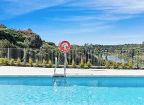 A swimming pool with a no diving sign, surrounded by a fence, with a view of a hill and a building in the background. - Casa Oceana | Pool - Large Terrace - Gym (Estepona)