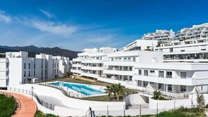 A modern white building with a swimming pool, surrounded by greenery and mountains in the background. - Casa Oceana | Pool - views - gym (Estepona)