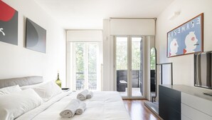 Een moderne slaapkamer met een groot bed, een televisie en een schuifdeur naar een buitengebied.