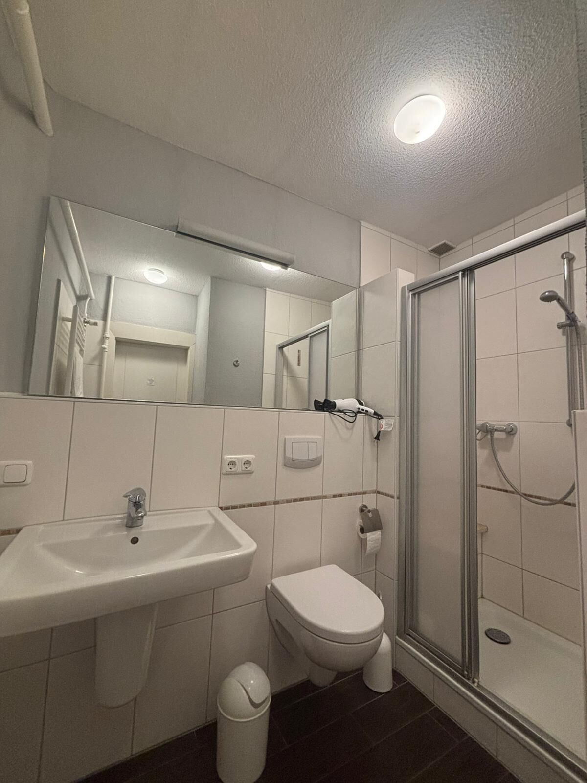 Une salle de bain équipée d’un lavabo, de toilettes et d’une douche à parois de verre.