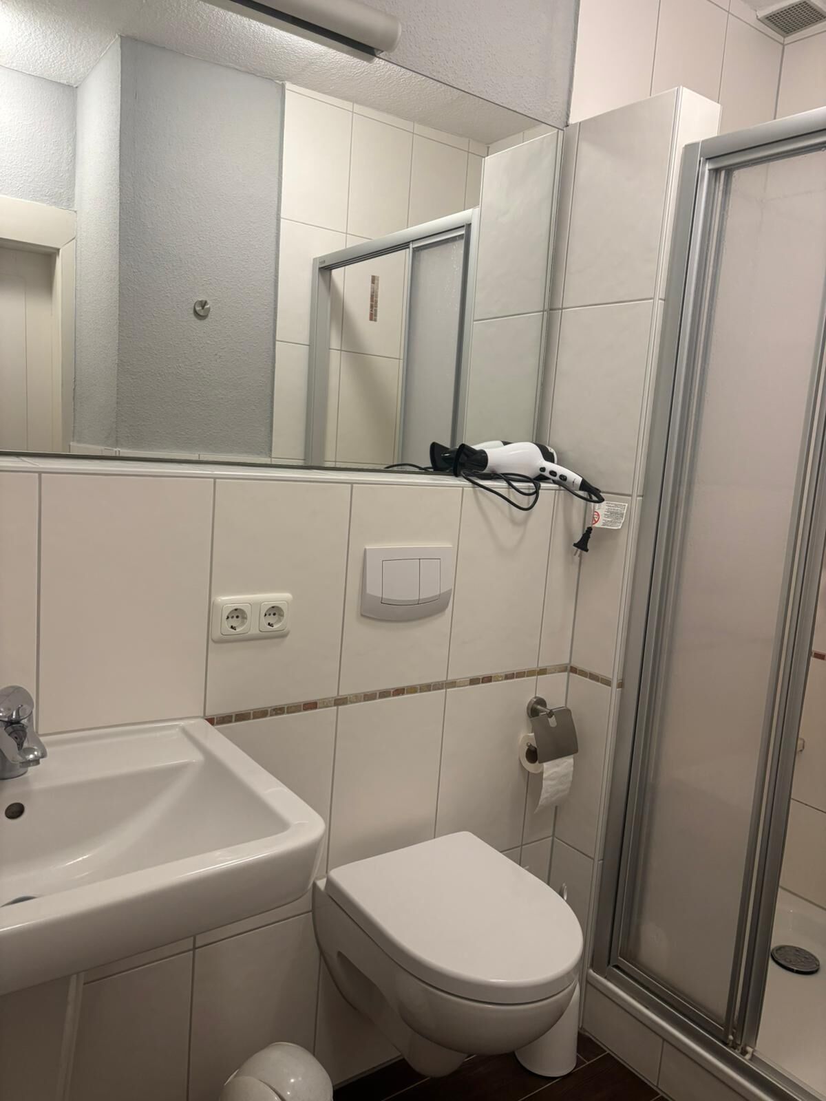 Un baño con lavamanos, inodoro y cabina de ducha de vidrio.