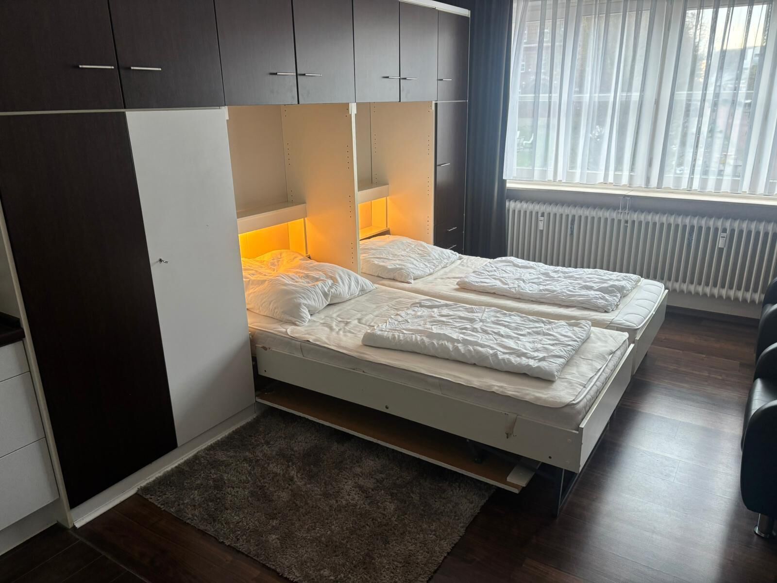 A bedroom with a bed, wardrobe, and a window.