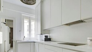 Cozinha moderna com armários brancos, pia de aço inoxidável e janela que oferece iluminação natural.