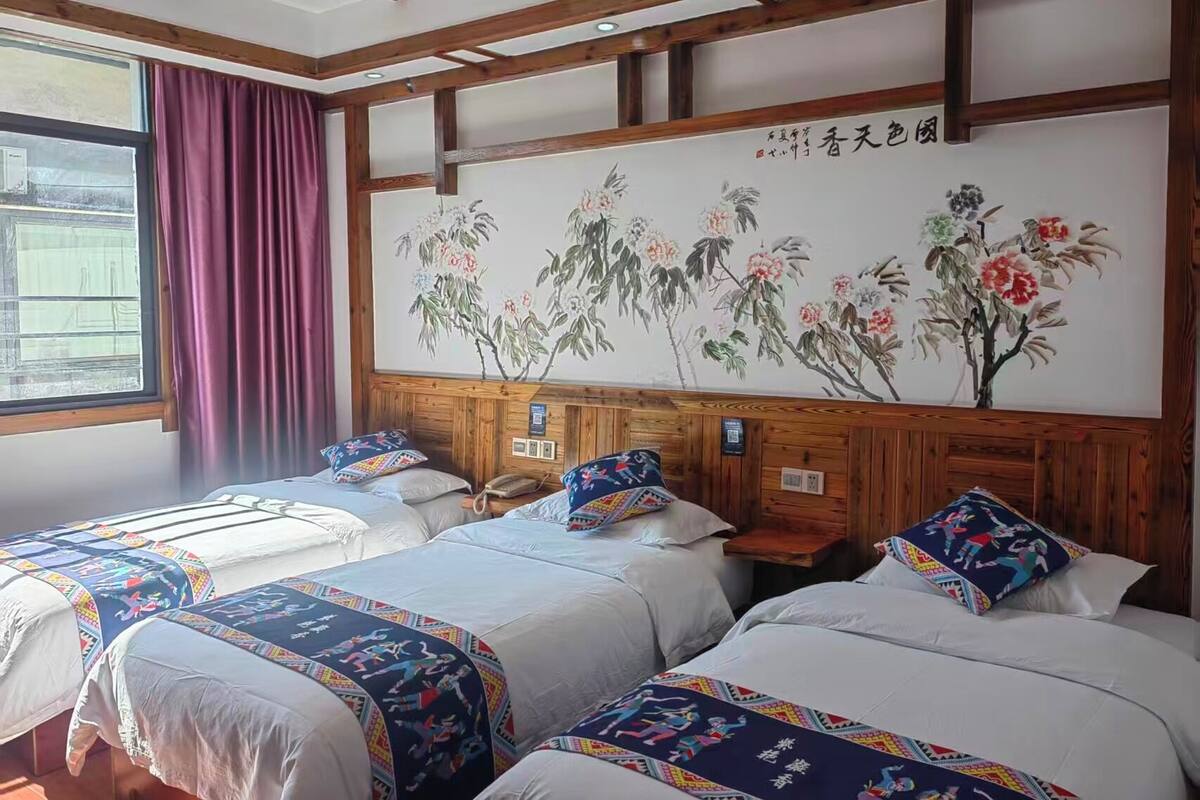 Ein Hotelzimmer mit zwei Betten, einem Holzkopfende und einem großen Blumenbild an der Wand.