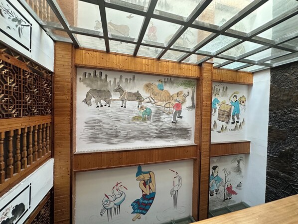 A room with wooden paneling and artwork depicting rural scenes. - Mountain View Guesthouse (Zhangjiajie)