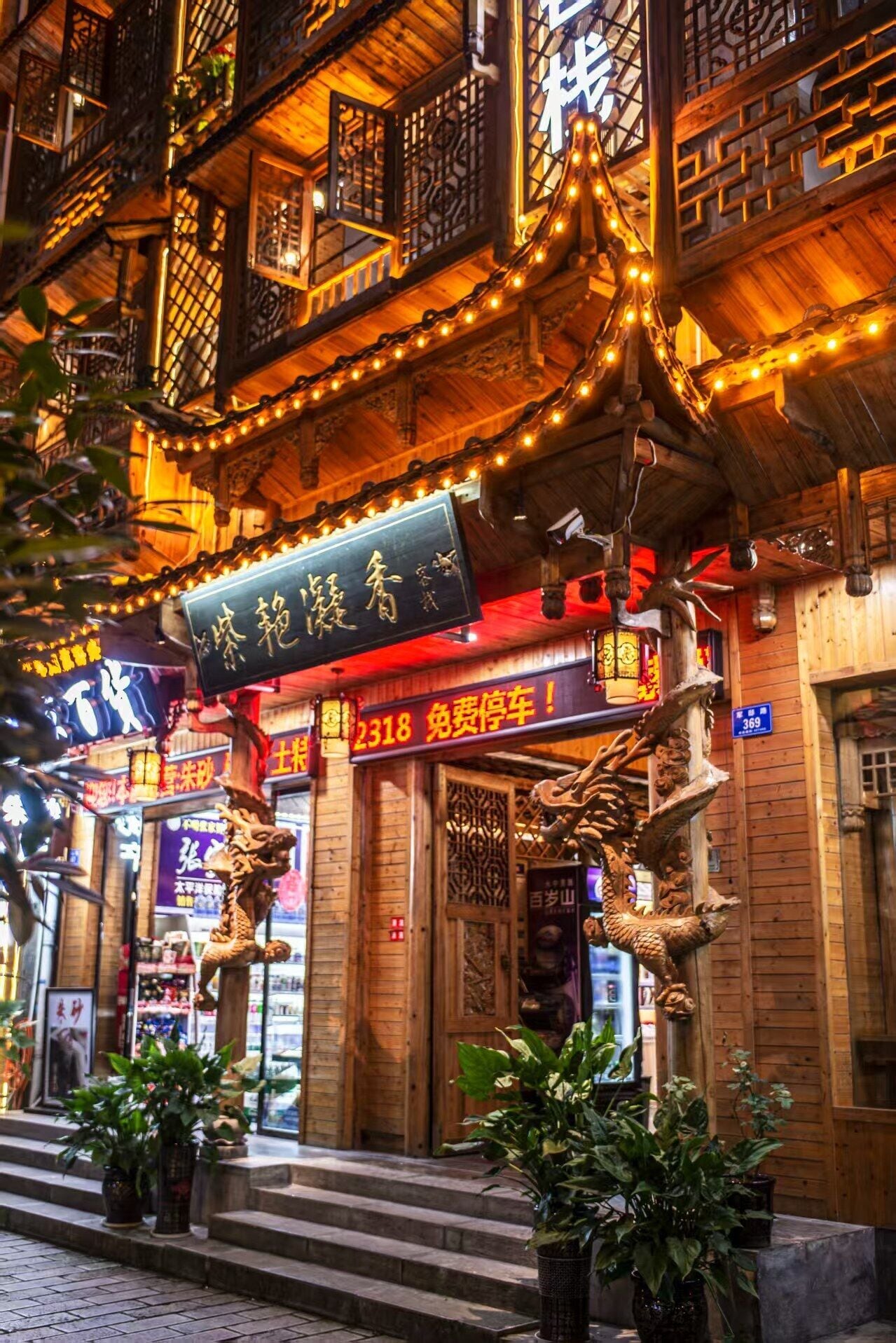A traditional wooden building with ornate decorations, a signboard, and potted plants.