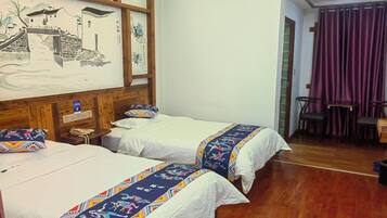 Une chambre avec deux lits, des têtes de lit en bois, une fresque murale et une vue sur un coin repas.
