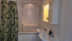 Ein Badezimmer mit Badewanne, zwei Waschbecken und Dusche.