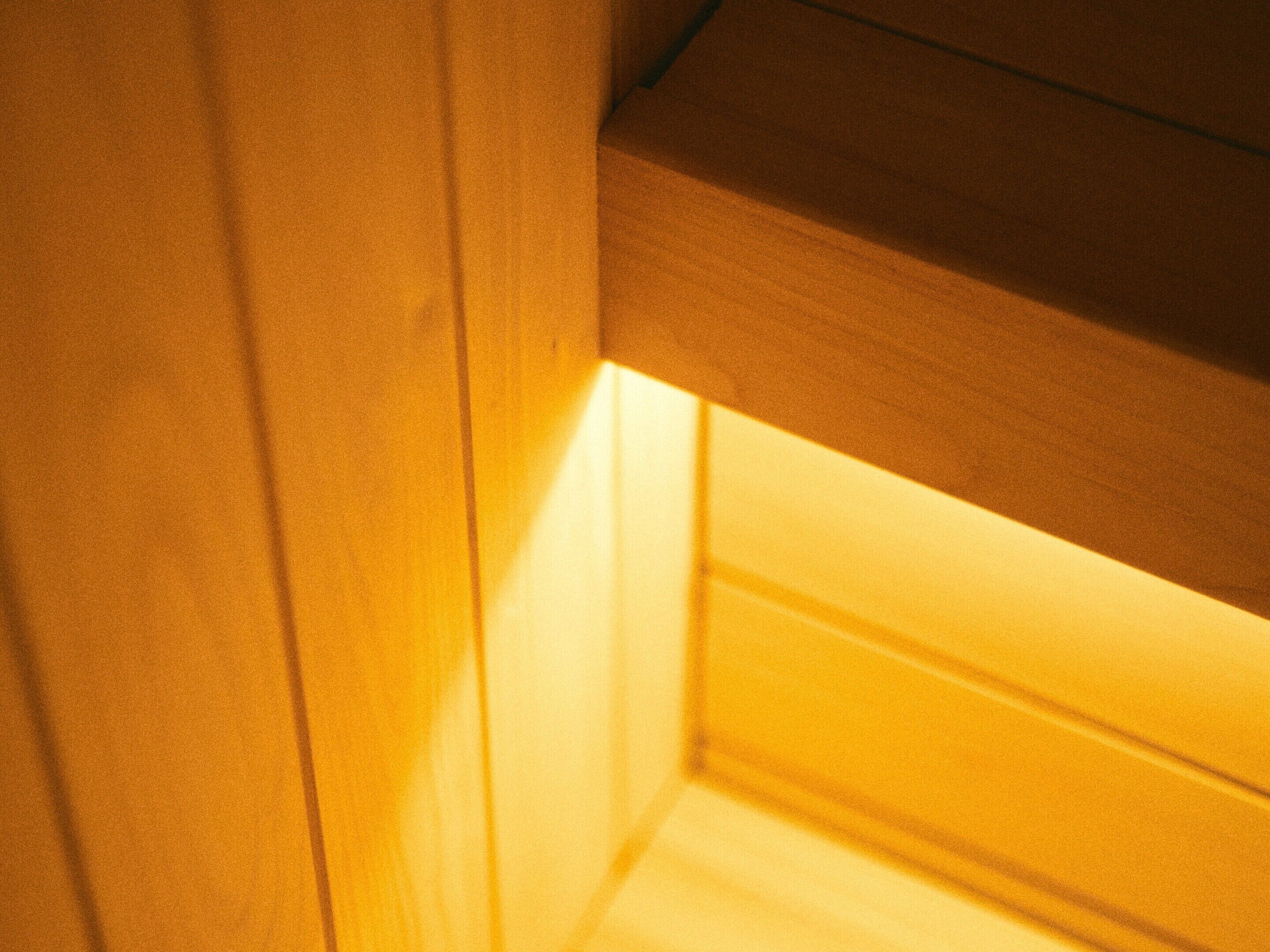 Primer plano de una estructura de madera con una cálida fuente de luz, posiblemente un rincón de habitación o detalle arquitectónico.