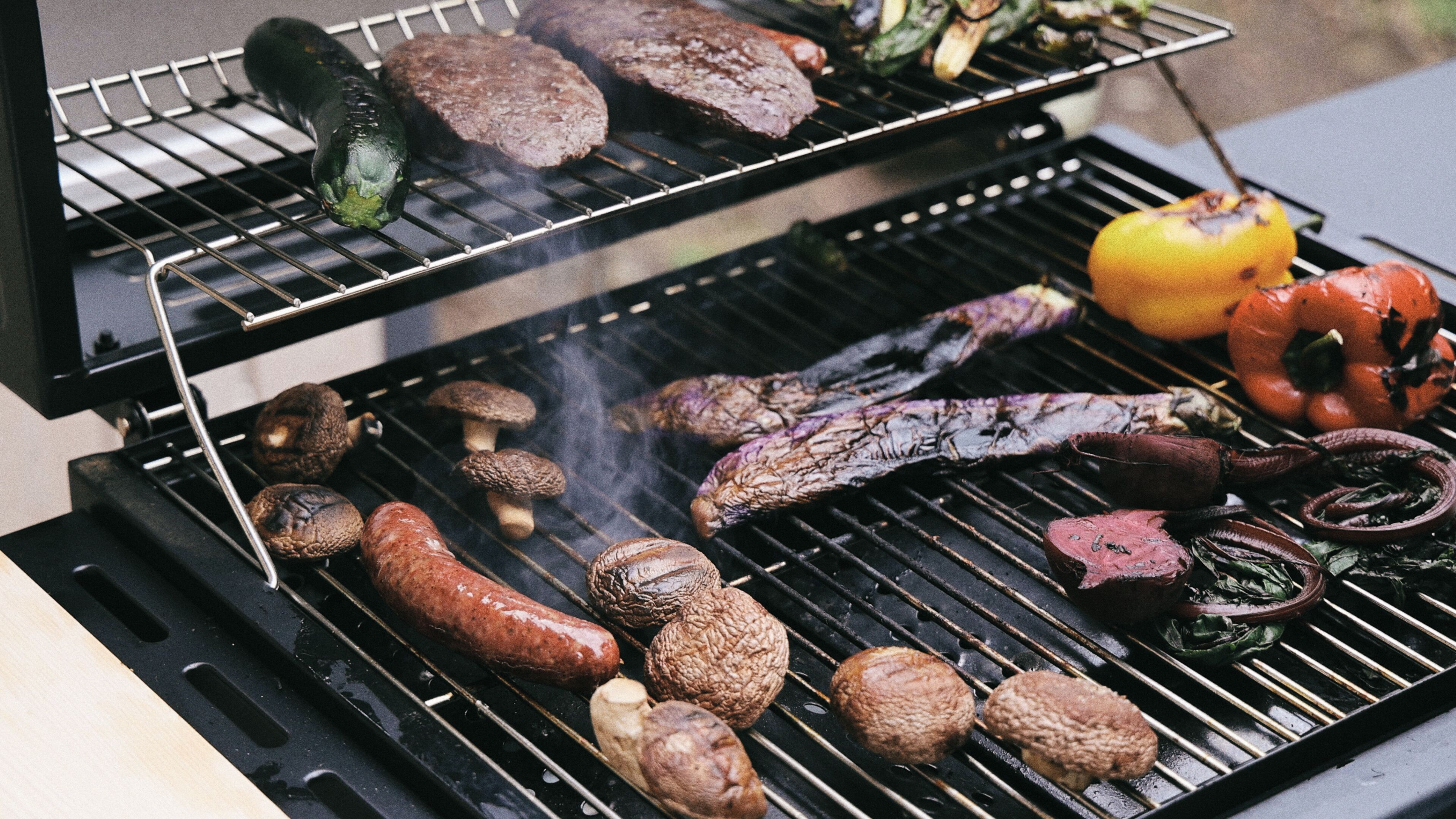 A grill with various meats and vegetables being cooked.