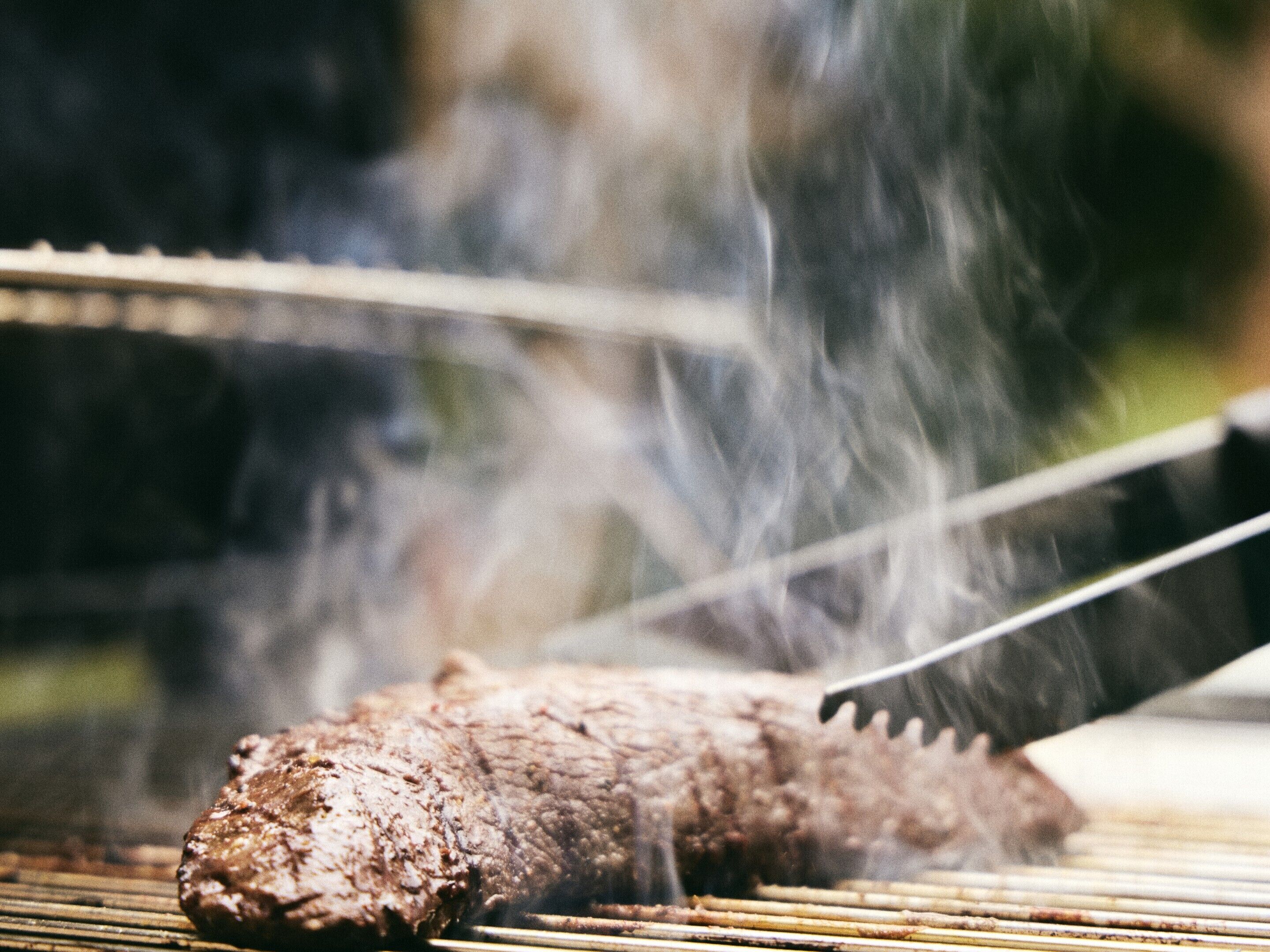Ein Nahaufnahme von gegrilltem Fleisch mit deutlichen Grillstreifen und Dampf, was darauf hindeutet, dass es zubereitet wird.