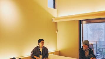 A room with two beds, a window with a view, and a wooden ceiling.