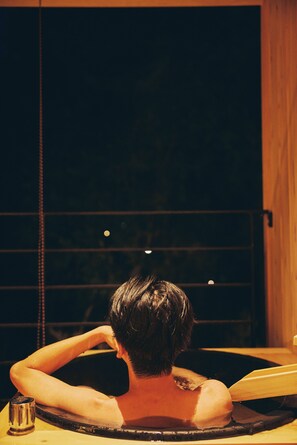 A person in a bathtub with a wooden interior and a window in the background. - GEOSPOT MOTOHAKONE A (Hakone)