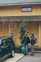 Un edificio con fachada de madera, una ventana y un pequeño árbol en primer plano.
