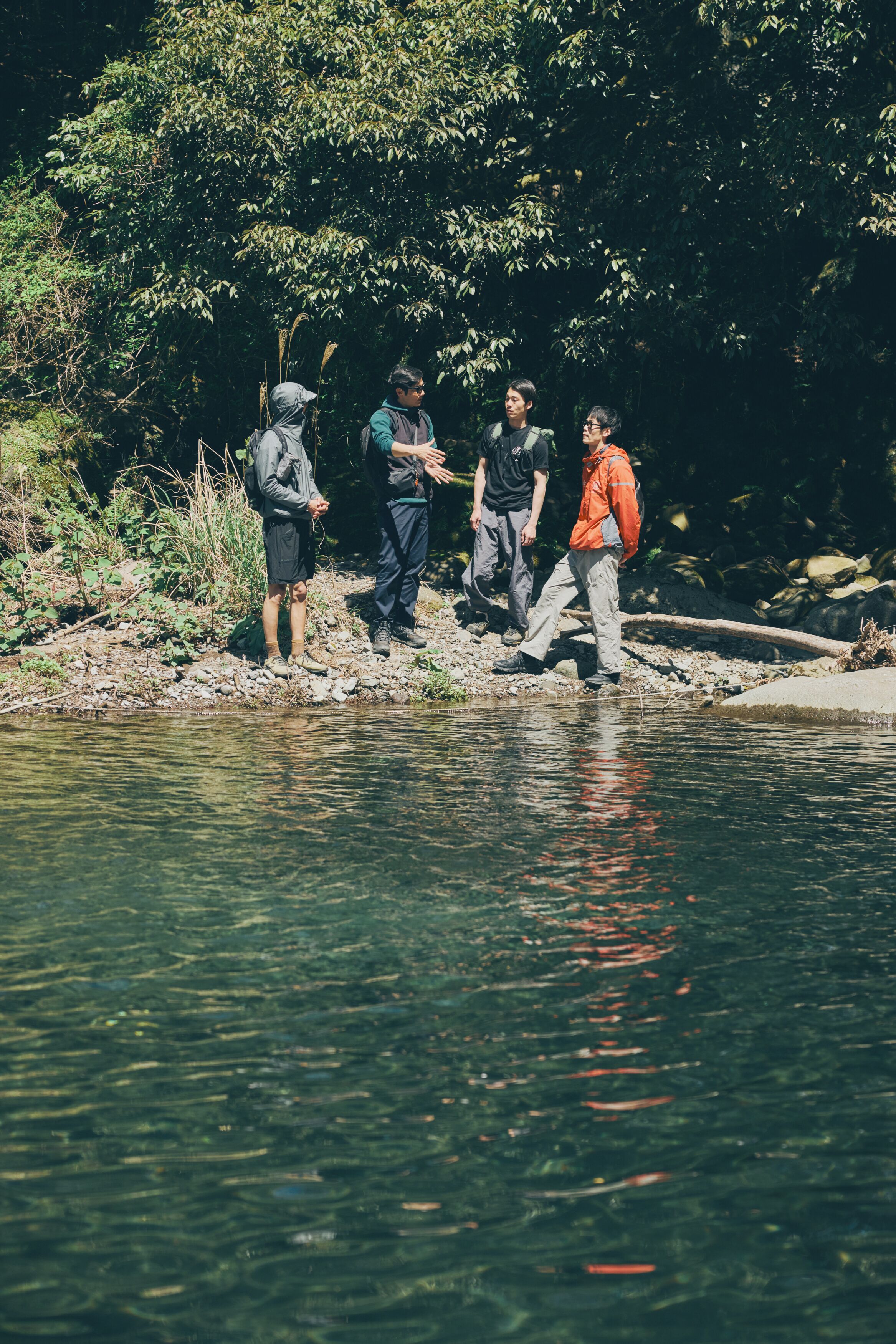 A group of people standing by a riverbank.