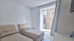 Una habitación de hotel moderna con dos camas, un escritorio y un amplio ventanal con vistas a la ciudad.