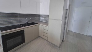 Una cocina moderna con estufa negra, armarios blancos y salpicadero de azulejos.