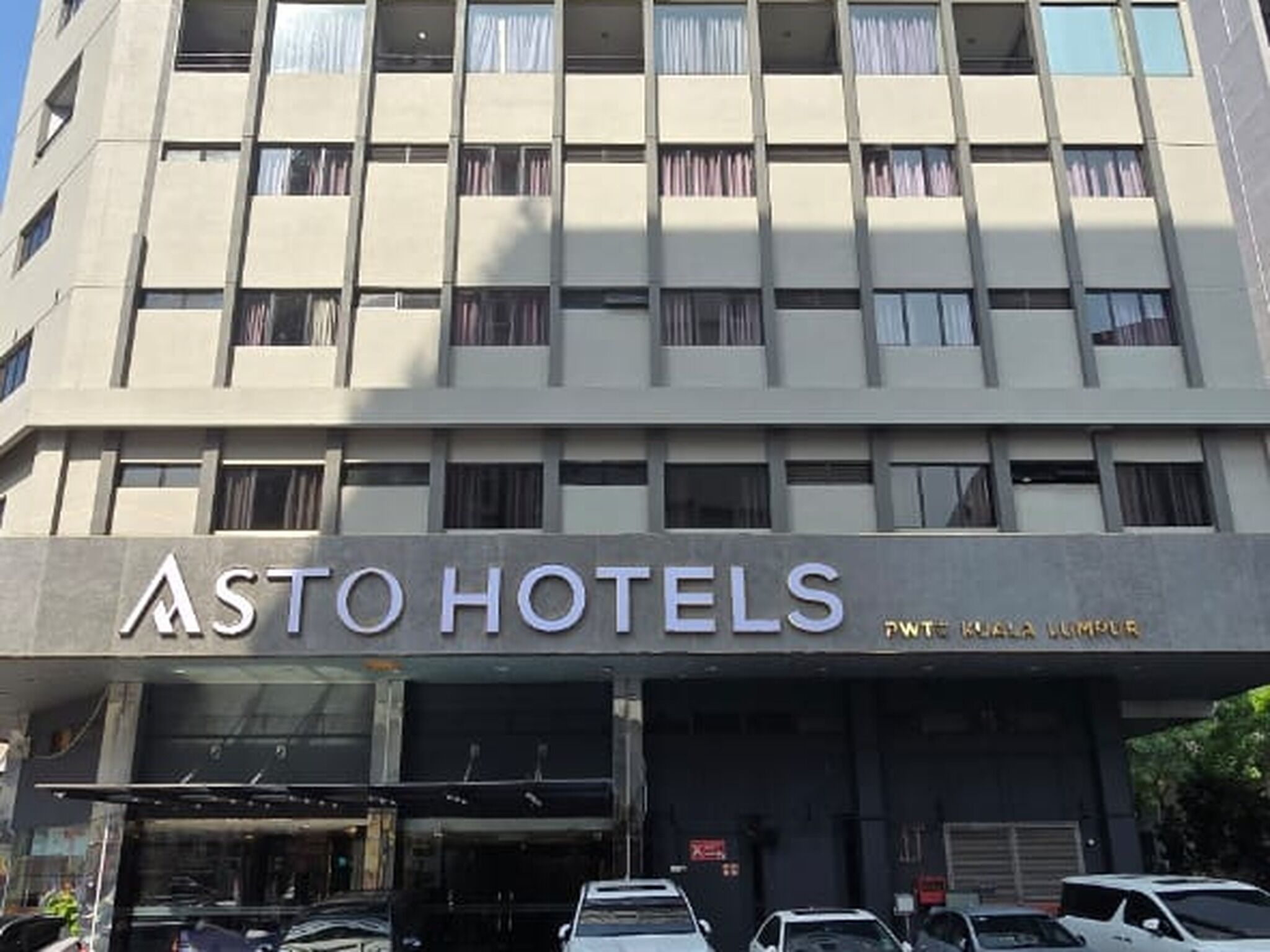 Un bâtiment portant les enseignes « ASTO HOTELS » et « PWT KUALA LUMPUR », ce qui indique qu’il s’agit d’un hôtel situé à Kuala Lumpur.