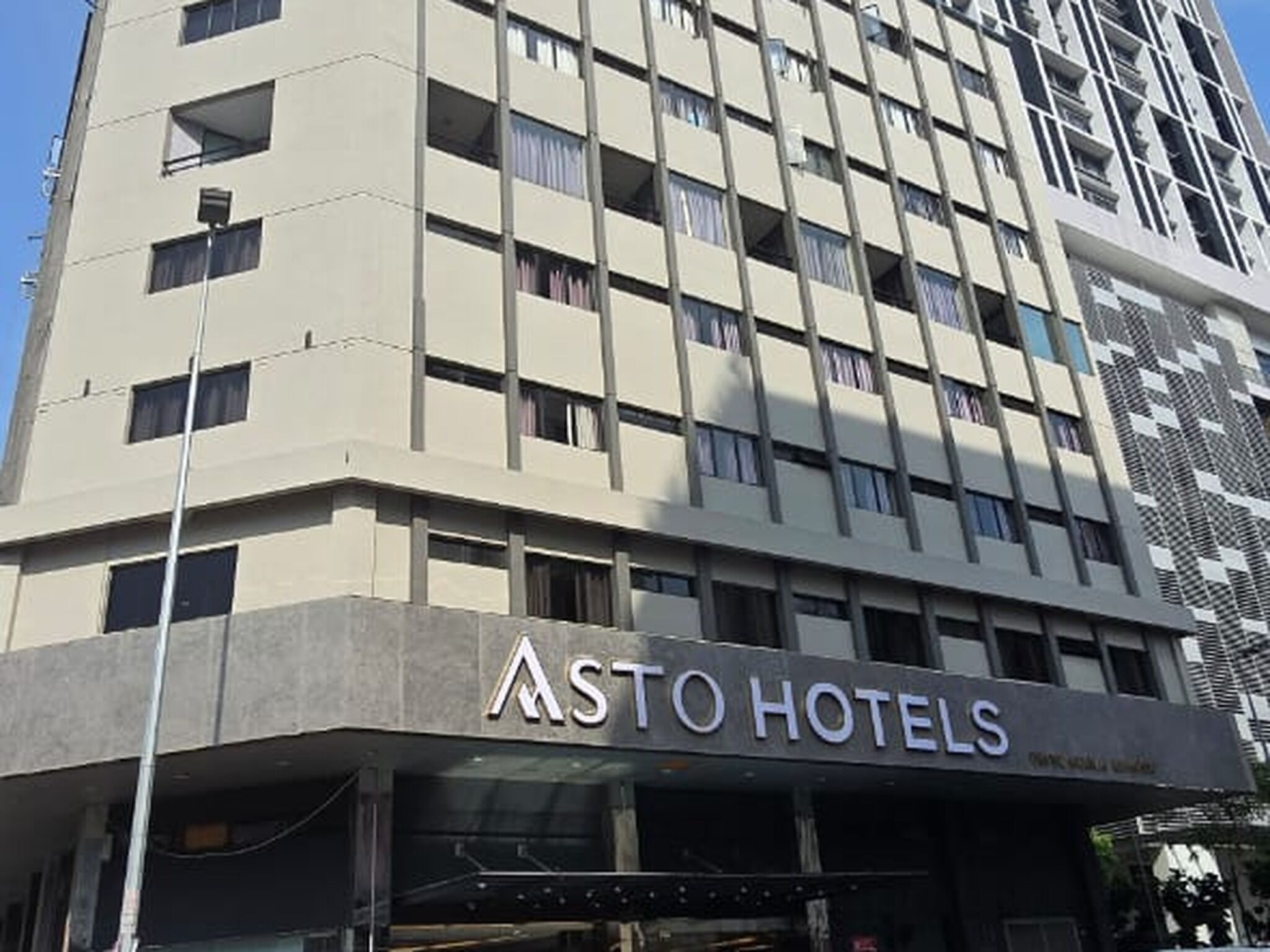 A multi-story hotel building with a modern design, featuring a prominent 'ASTO HOTELS' sign at the ground level.