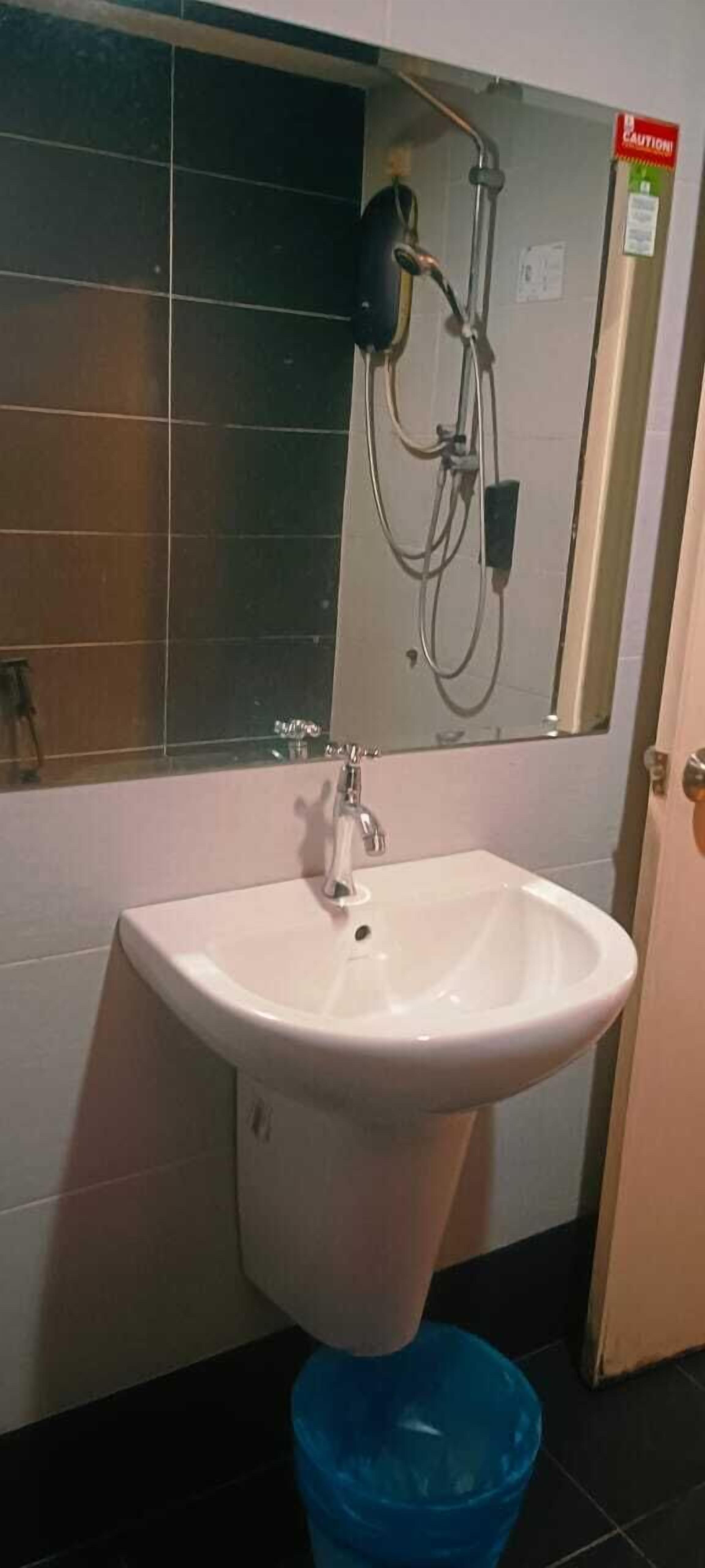 A bathroom with a white sink, a mirror, and a shower with a red caution sign.