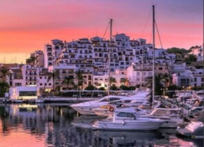 Ein Yachthafen mit vertäuten Booten, ein Gebäude am Wasser und ein Sonnenuntergangshimmel.