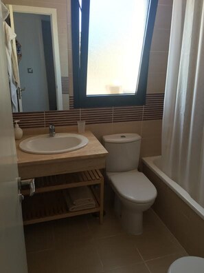 A compact bathroom with a wooden vanity, a white sink, a toilet, and a bathtub. - PENTHOUSE IN MORAIRA, WITH A LARGE TERRACE   (VC)