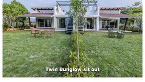 A modern house with a large backyard, a small tree, and outdoor furniture. - The Quade Villa By Spandan Holiday Homes (Anjaneri)
