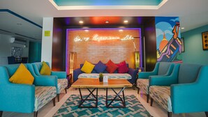 Un espace de détente moderne avec des canapés de couleur turquoise, une table basse en bois et des coussins aux couleurs vives.