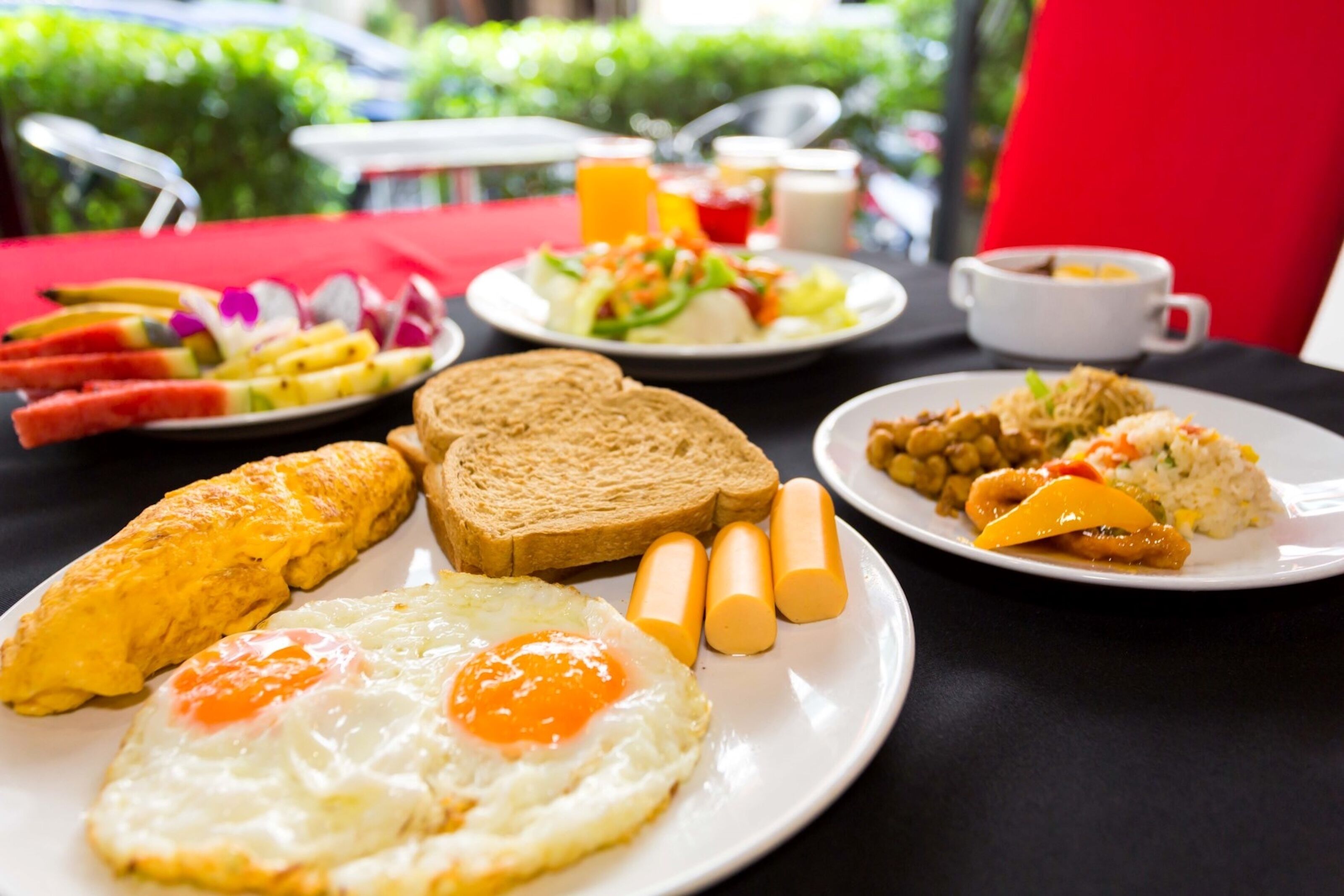 A breakfast table with plates of toast, eggs, and vegetables, along with a cup of coffee.