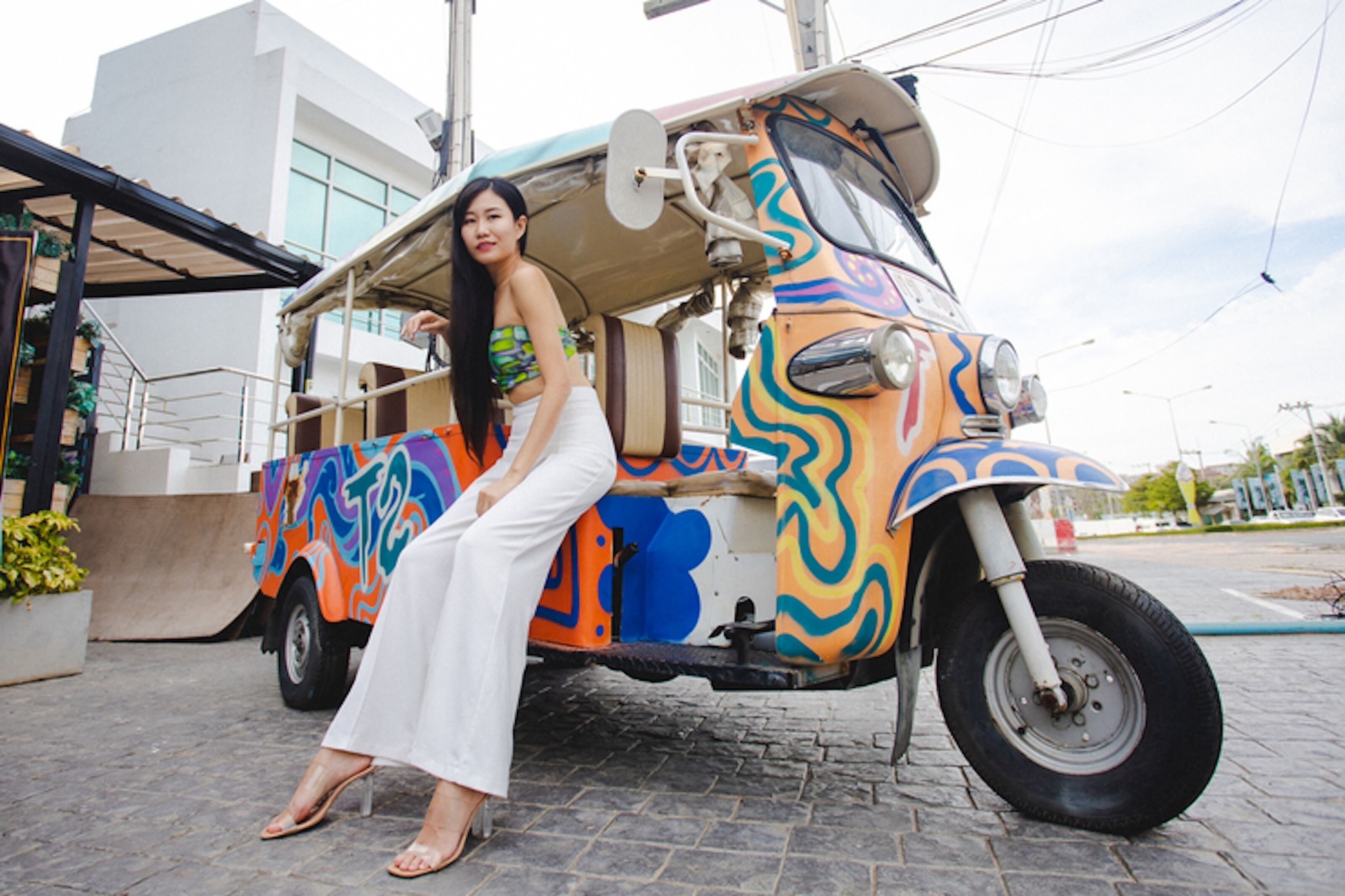 A colorful three-wheeled vehicle parked in front of a building with a modern architectural style.