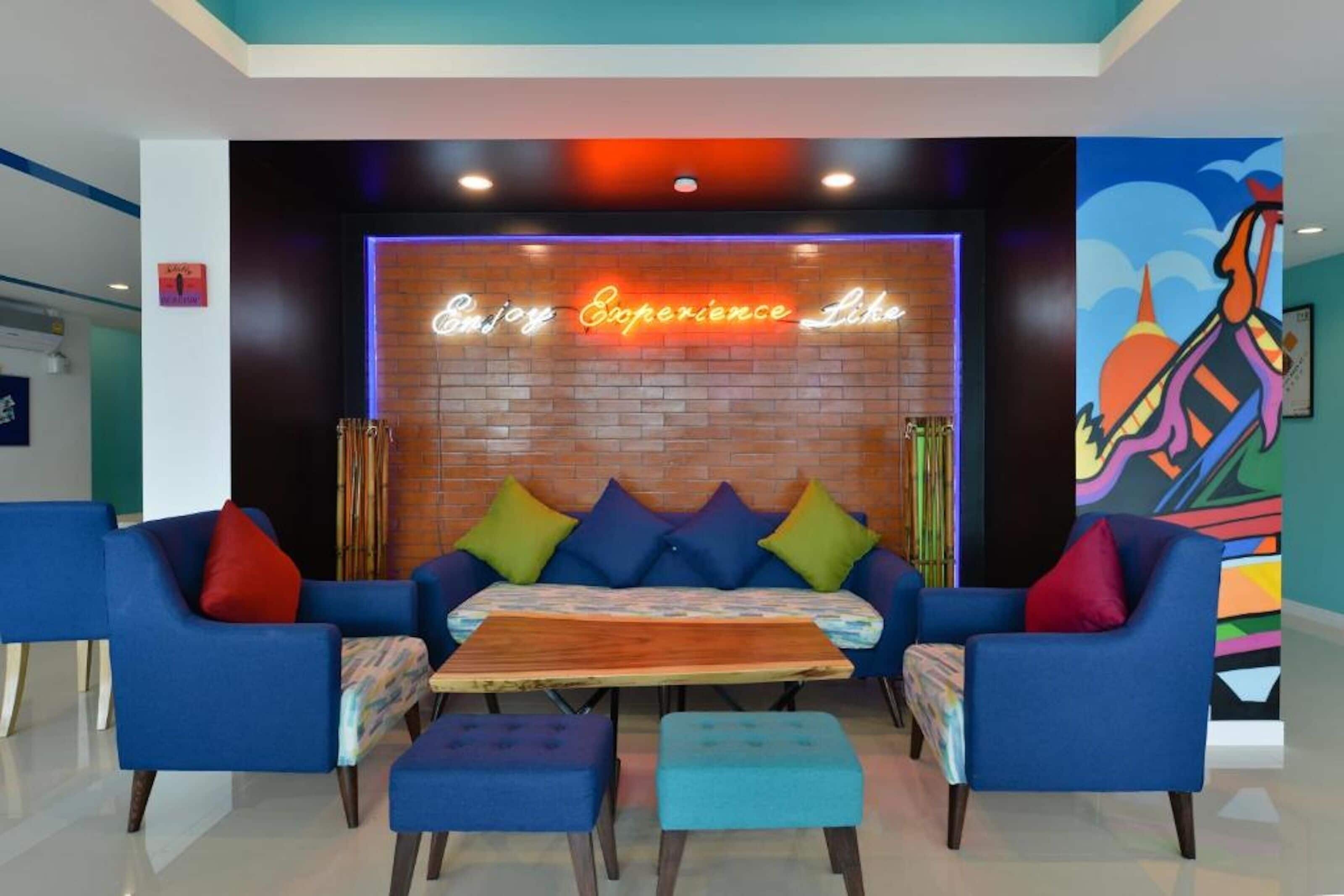 Een moderne lounge met een neonbord, blauwe banken en een houten tafel.