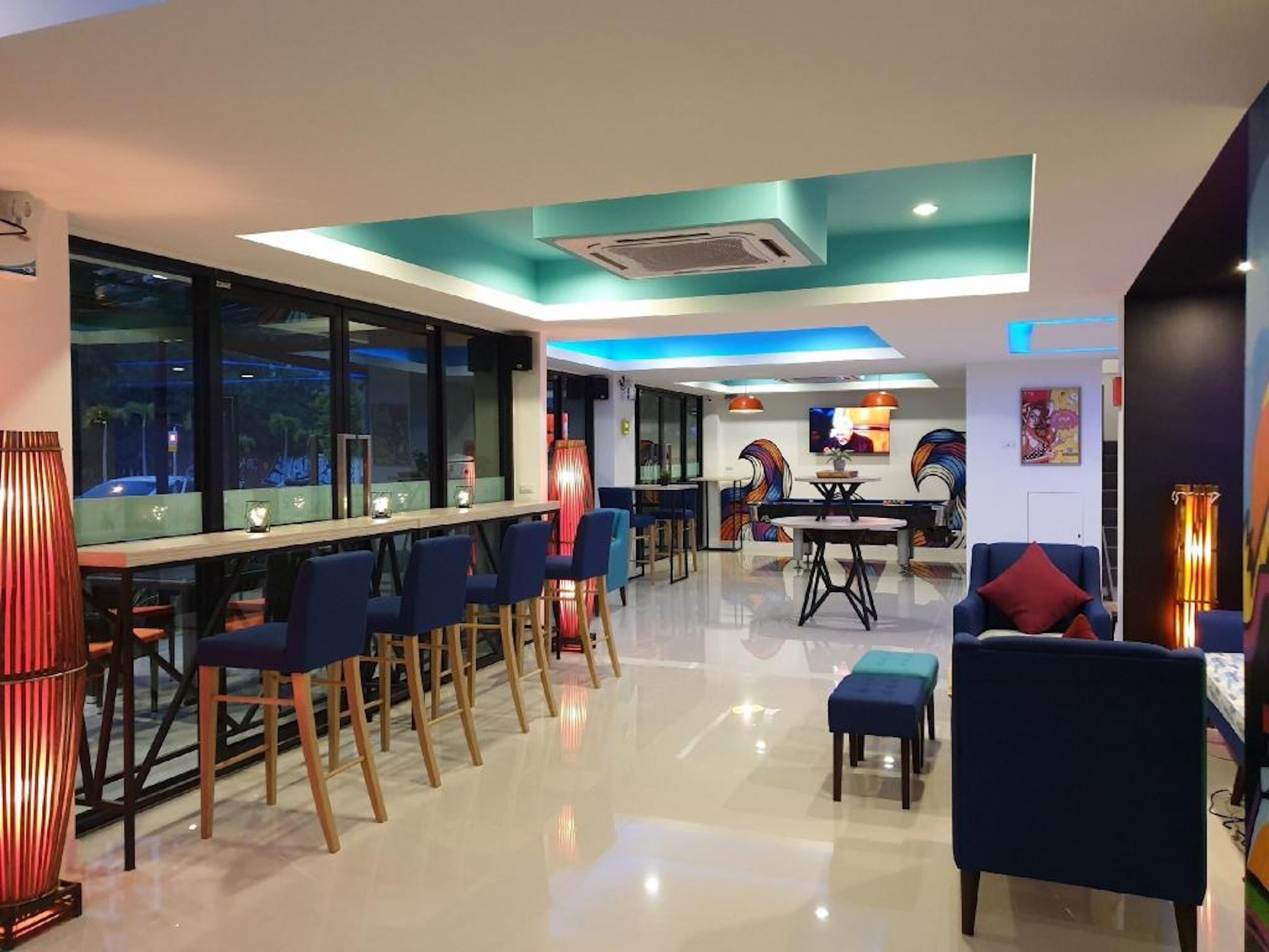A modern bar area with a long counter, multiple bar stools, and a seating area with a table and chairs.