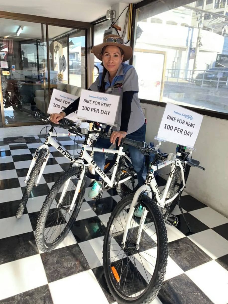 A person holding two bicycles with signs indicating a rental price of 100 per day.