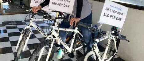 A person holding two bicycles with signs indicating a rental price of 100 per day.
