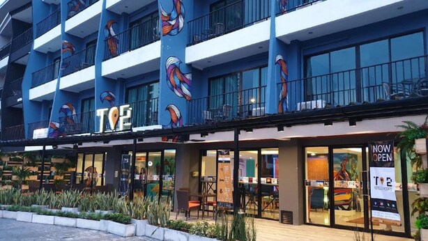 Un hôtel à la façade bleue, doté de nombreux balcons et d’une enseigne indiquant qu’il est désormais ouvert.
