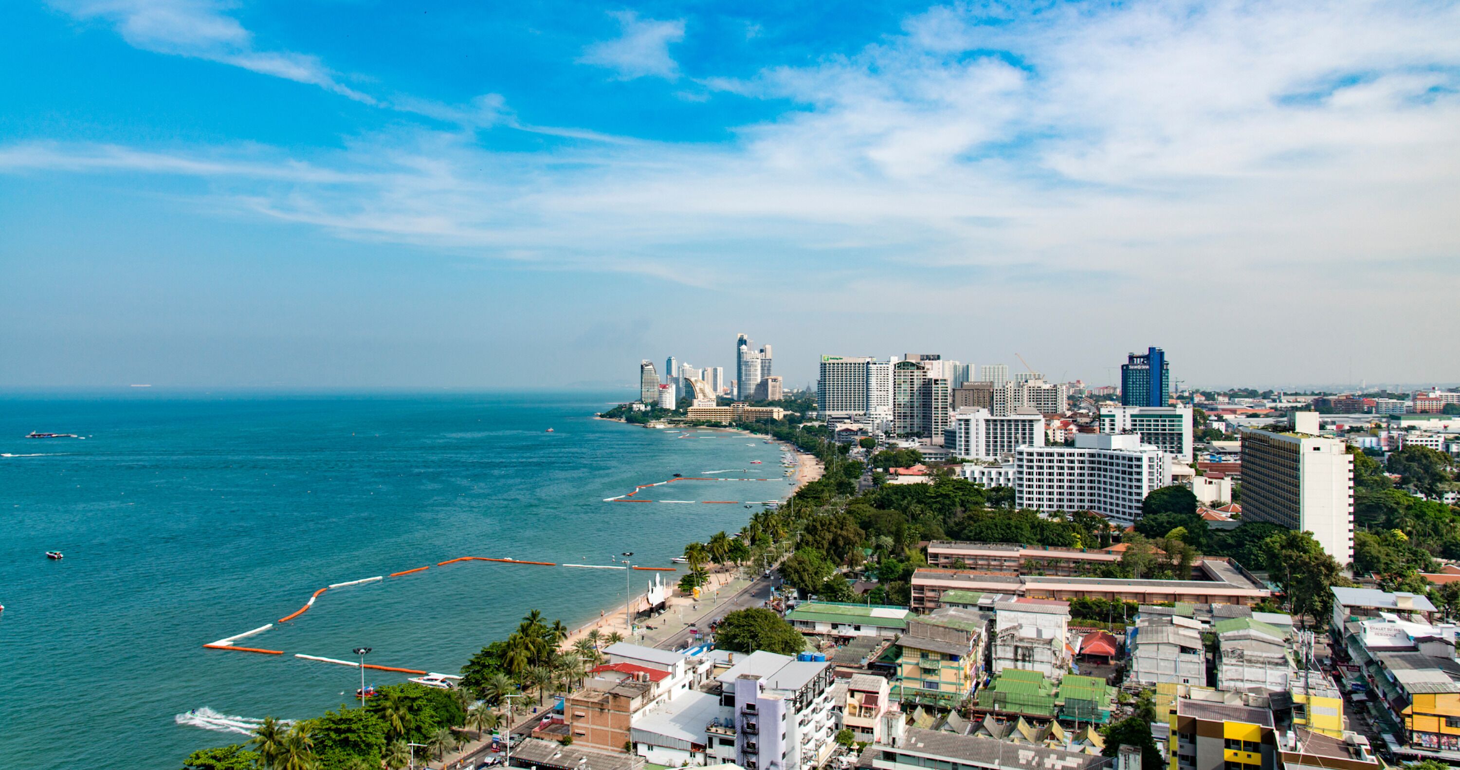 A coastal cityscape with high-rise buildings, a beach, and a clear sky.