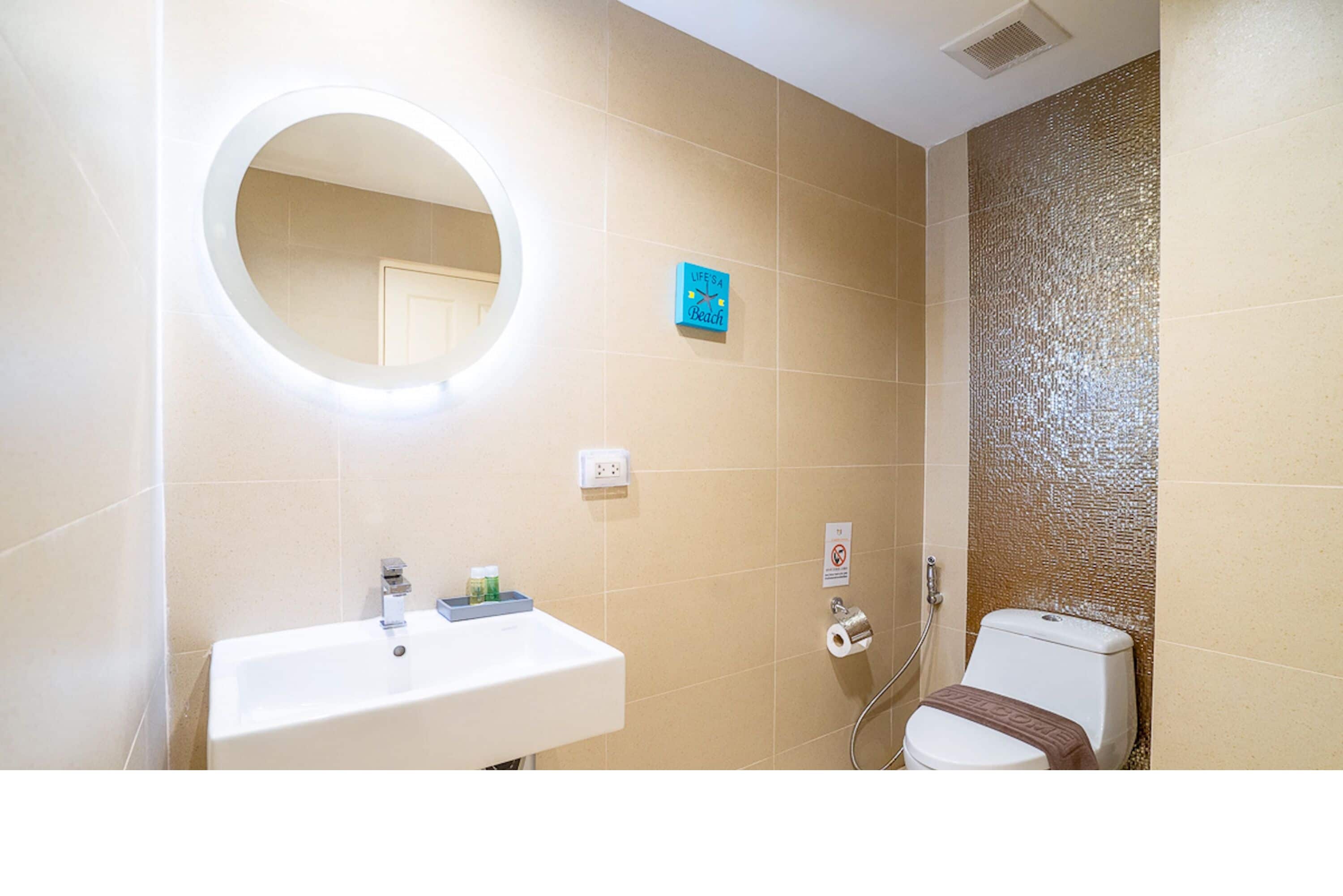 Baño con lavamanos, espejo, inodoro y ducha.